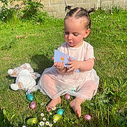 Amalia a rejoint le concours — aidez-le/la à gagner de superbes lots ! child, toddler, grass, easter_eggs, plush_toy, card, outdoor, sunlight, greenery, flowers, barefoot, dress, hairstyle, playing, nature, garden, summer, cute, sitting, toy