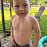toddler, child, shirtless, wet, water_droplets, outdoor, backyard, grass, swing_set, plastic_pool, summer, playtime, shorts, camouflage, lawn_chair, daylight, person, young_child, happy, portrait