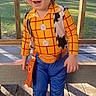 child, toddler, costume, woody, toy_story, outdoor, deck, wood, barefoot, smiling, curly_hair, sunlight, trees, grass, playful, happy, clothing, person, portrait, daylight