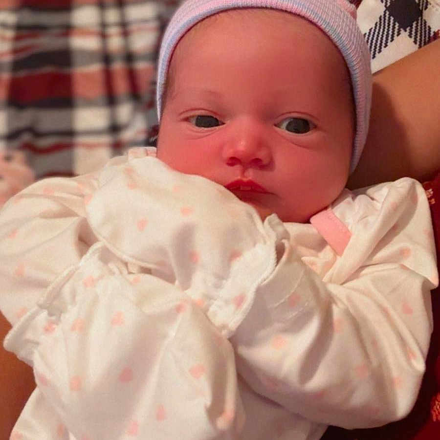 Serenah is registered to the contest to win money with this photo: baby, baby_garment, beanie, closeup, clothing, cute, face, headwear, human, indoors, infant, newborn, person, pink_hearts, portrait, resting, sleepwear, soft_lighting, warm, white_outfit