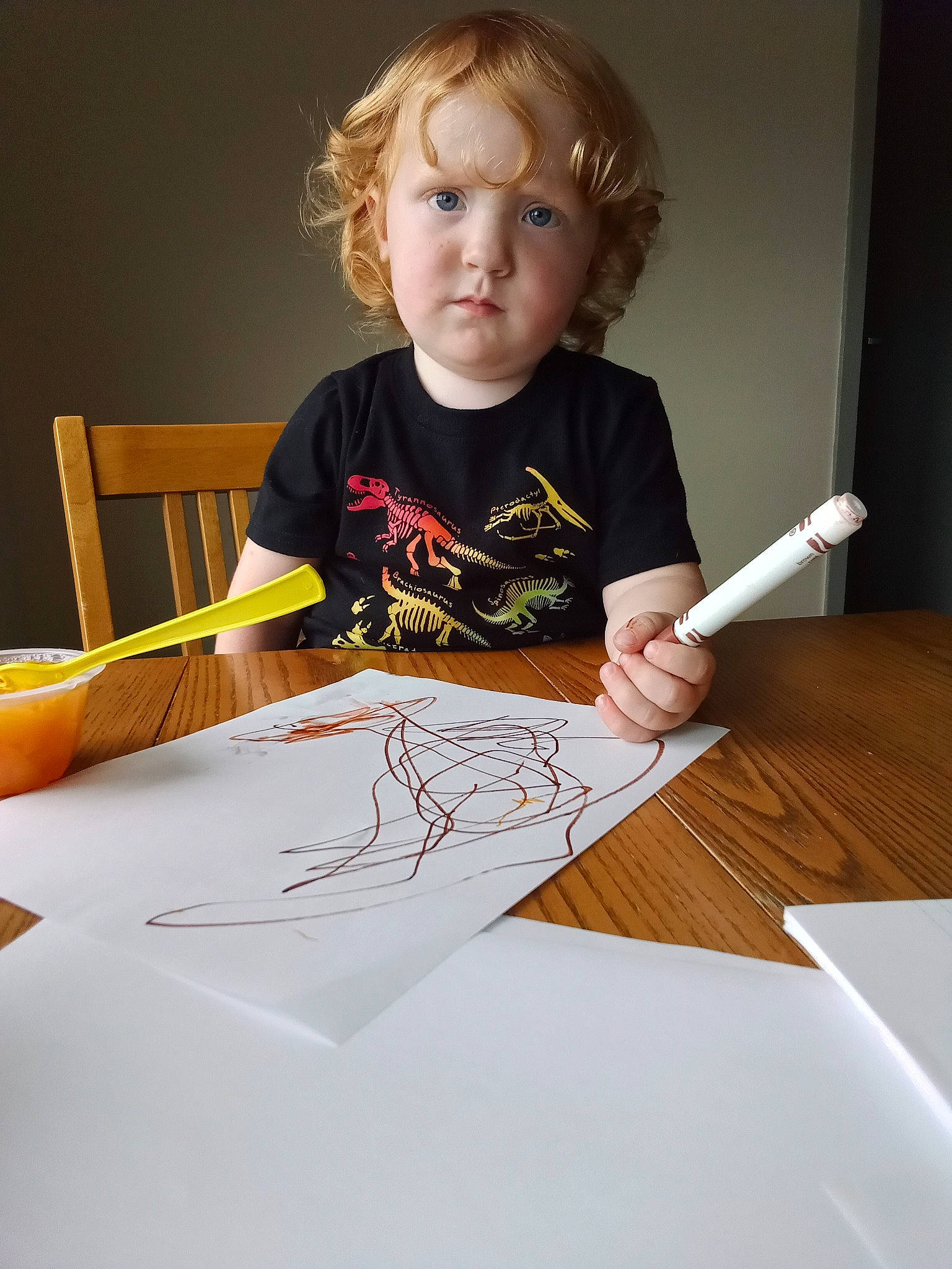 River is registered to the contest to win money with this photo: art, chair, child, desk, drawing, homework, office_instrument, office_supplies, pen, pencil, person, stationery, t_shirt, table, tableware, toddler, visual_arts, wood, writing, writing_implement