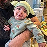 baby, child, adult, glasses, long_hair, beard, hat, yoda, smile, indoor, water_cooler, holding, clothing, sitting, person, arm, toy, furniture, floor, portrait