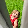 Liala joined the competition — help win amazing prizes! child, toddler, red_dress, curious, peeking, hand, green_background, outdoor, grass, portrait, cute, smiling, baby, person, young_child, playful, summer, daylight, skin, hair