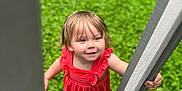 Liala is registered to the contest to win money with this photo: toddler, child, red_dress, outdoor, greenery, grass, wooden_stairs, railing, barefoot, happy, smiling, portrait, looking_up, curious, summer, nature, young_child, cute, daylight, playful