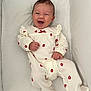 Ava a rejoint le concours — aidez-le/la à gagner de superbes lots ! baby, smiling, infant, onesie, white_clothing, red_flowers, happy, lying_down, cushion, soft_surface, cute, child, portrait, indoors, small_hands, footed_pajamas, young_child, cheerful, face, joyful