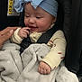 baby, child, headband, blue, blanket, car_seat, hand, smile, clothing, safety_harness, person, infant, indoor, cute, happy, soft, warm, cozy, portrait, closeup