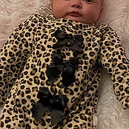 Kehlani is registered to the contest to win money with this photo: baby, infant, leopard_print, onesie, black_bows, blanket, fluffy, soft, cute, lying_down, sleepwear, child, portrait, face, eyes, skin, head, cozy, comfortable, indoor