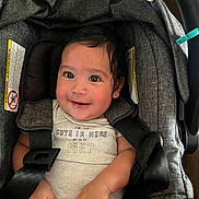 Tommy is registered to the contest to win money with this photo: baby, car_seat, child, closeup, clothing, cute, expression, face, hair, hands, happy, indoors, infant, infant_care, onesie, person, safety, seat, smile, straps