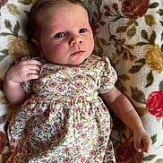 Rosaleigh is registered to the contest to win money with this photo: baby, infant, child, floral_dress, blanket, pattern, face, hand, skin, person, lying_down, cute, young, indoors, portrait, expression, newborn, soft, comfortable, clothing