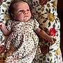 baby, infant, child, floral_dress, blanket, pattern, flower, laying_down, cute, skin, face, expression, hand, arm, leg, indoors, soft_texture, young, portrait, relaxing