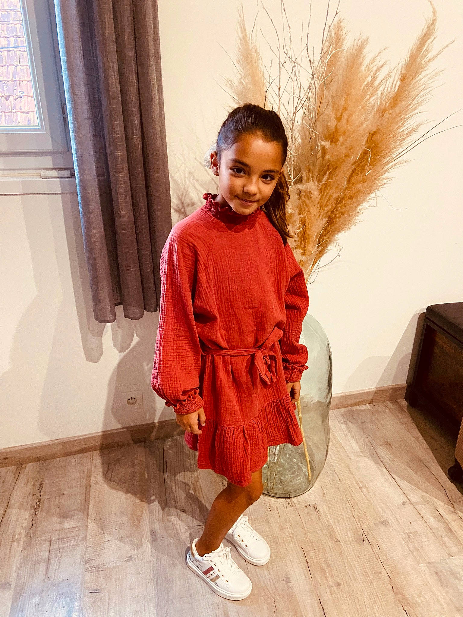 Keylia participe au concours pour gagner de l'argent avec cette photo : curtain, fashion_design, floor, flooring, fun, happy, hardwood, human_leg, joy, knee, pattern, peach, person, sleeve, smile, standing, thigh, toddler, waist, wood