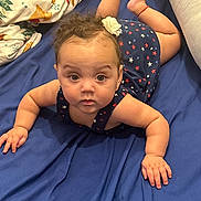 Milayshka joined the competition — help win amazing prizes! baby, infant, child, blue_dress, star_pattern, flower_hair_clip, curly_hair, lying_down, bed, blue_sheet, blanket, pillow, indoor, cute, chubby_cheeks, hands, face, eyes, skin, person