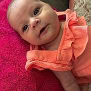 Alayna Babylove joined the competition — help win amazing prizes! baby, infant, face, child, pink_towel, orange_clothing, ruffles, portrait, cute, smile, skin, head, lying_down, young_child, indoor, closeup, expression, person, soft_texture, bright_colors
