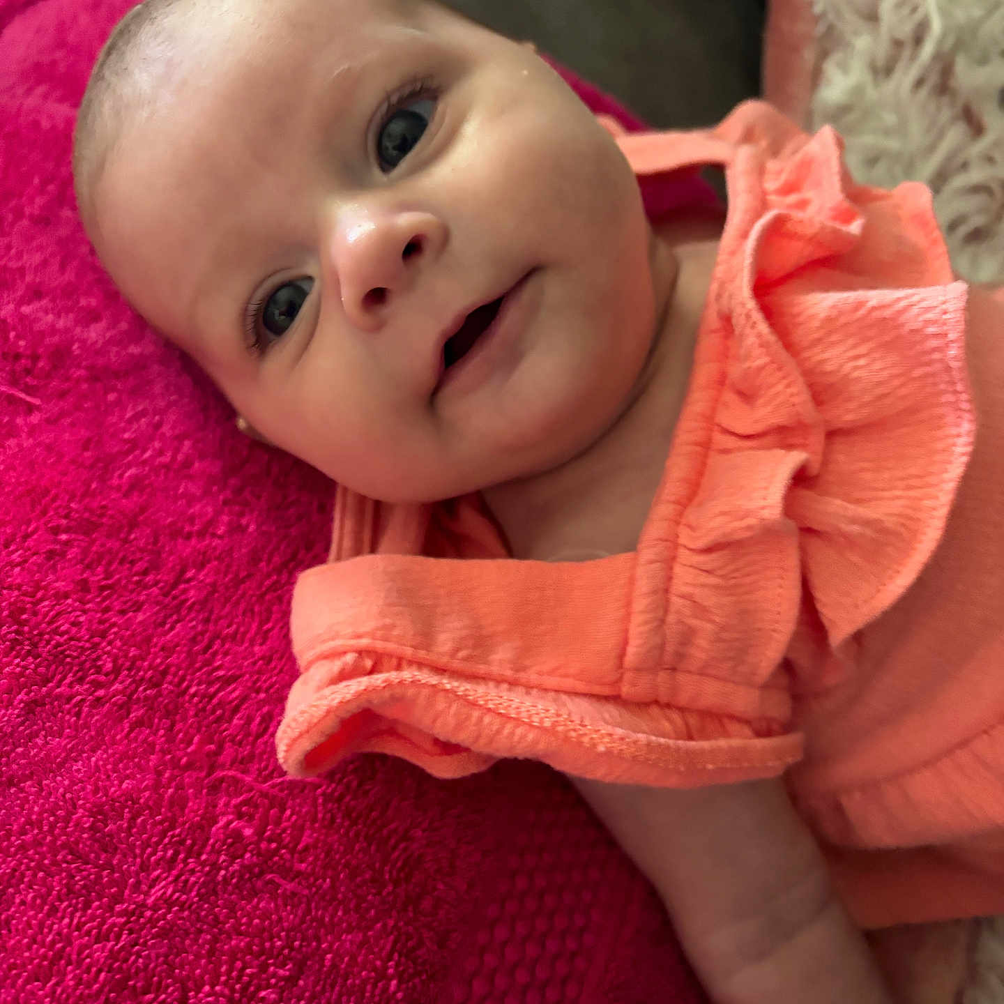 Alayna Babylove joined the competition — help win amazing prizes! baby, bright_colors, child, closeup, cute, expression, face, head, indoor, infant, lying_down, orange_clothing, person, pink_towel, portrait, ruffles, skin, smile, soft_texture, young_child