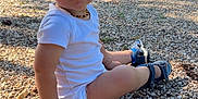 Tylio participe au concours pour gagner de l'argent avec cette photo : toddler, child, outdoor, playground, slide, gravel, sitting, white_clothing, sandals, happy, smiling, nature, greenery, sunlight, hair, necklace, bracelet, baby, person, daytime