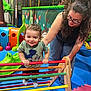 Tylio participe au concours pour gagner de l'argent avec cette photo : child, toddler, woman, playground, indoor, colorful, toy, smiling, support, play_area, clothing, glasses, hair, floor_mat, wooden_toy, activity, happy, person, interaction, leisure