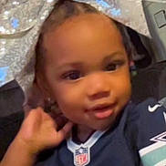 Ember is registered to the contest to win money with this photo: toddler, child, face, bow, glitter, jersey, football, sportswear, hand, smile, indoor, couch, person, cute, headwear, young_child, apparel, portrait, casual, happy