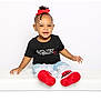 toddler, child, smiling, red_bow, black_tshirt, jeans, frills, red_shoes, sitting, white_bench, portrait, cute, happy, fashion, studio, young_child, accessories, casual_clothing, playful, bright
