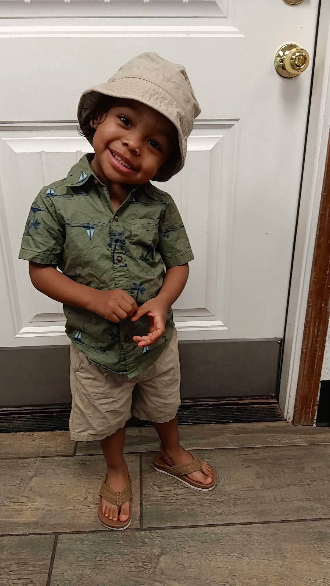 Zaydyn is registered to the contest to win money with this photo: cap, child, door, eye, fashion_accessory, happy, hat, headgear, headwear, joy, military_camouflage, military_uniform, pattern, person, sandal, sleeve, slipper, smile, standing, sun_hat
