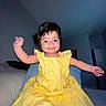 Sophia joined the competition — help win amazing prizes! arms_raised, baby, bed, bedroom, brown_eyes, child, dark_hair, dress, fabric, flash_photography, happy, home, indoor, infant, joyful, outstretched_arms, portrait, sitting, smiling, yellow_dress