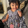 bees, blanket, brown_eyes, child, couch, dark_hair, dress, family_photo, flowers, furniture, gingham, girl, hair_bows, happy, home, indoor, portrait, sitting, smiling, toddler