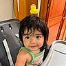 Sophia joined the competition — help win amazing prizes! baby, child, cute, dark_hair, face, furniture, green_clothing, high_chair, home, indoors, infant, looking_at_camera, mealtime, photography, portrait, rubber_duck, sitting, smiling, toddler, wooden_door
