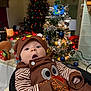 baby, infant, child, holiday, thanksgiving, christmas_tree, christmas_lights, decoration, festive, indoors, cozy, clothing, face, expression, surprised, cute, seasonal, celebration, holiday_decor, person