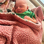 Jaeger is registered to the contest to win money with this photo: newborn, baby, sleeping, blanket, pink, green_clothing, smile, indoor, cozy, infant, face, wrapped, soft, cute, peaceful, child, resting, portrait, toddler, human