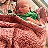 newborn, baby, sleeping, blanket, pink, green_clothing, smile, indoor, cozy, infant, face, wrapped, soft, cute, peaceful, child, resting, portrait, toddler, human