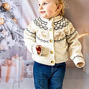 Penelope Roseanne is registered to the contest to win money with this photo: toddler, child, sweater, jeans, smile, face, blond_hair, earrings, holiday, christmas_tree, presents, indoor, portrait, festive, winter_clothing, cozy, cute, standing, background, warm_lighting