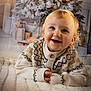 child, toddler, smiling, sweater, blanket, holiday, christmas_tree, presents, indoor, cute, happy, portrait, cozy, festive, decor, warm, baby, face, person, celebration