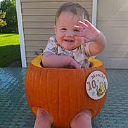 Amelia joined the competition — help win amazing prizes! baby, infant, child, smiling, waving, pumpkin_costume, halloween, autumn, outdoor, patio, chair, backyard, garage, house, sunlight, portrait, sitting, barefoot, happy, costume