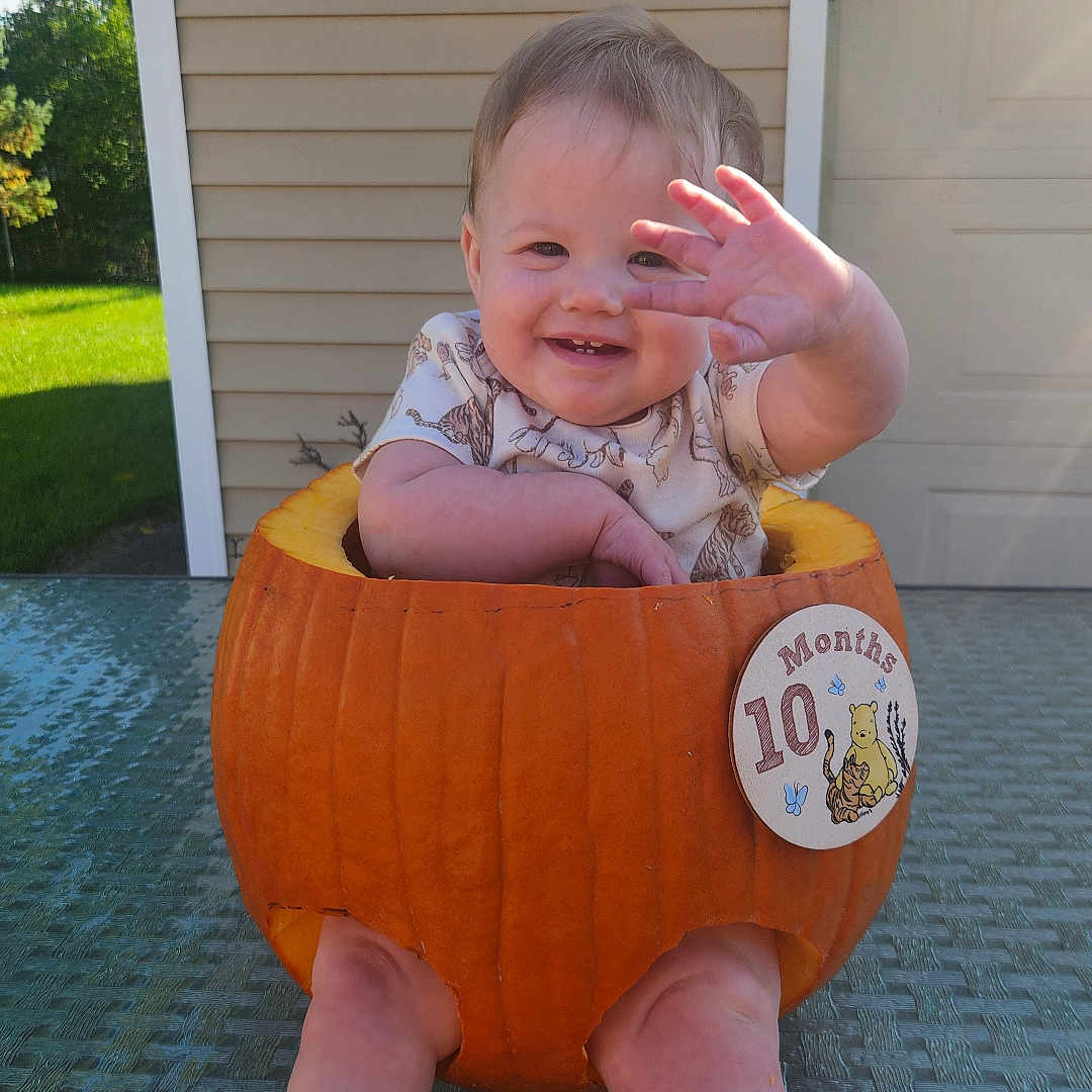 Amelia joined the competition — help win amazing prizes! baby, infant, child, smiling, waving, pumpkin_costume, halloween, autumn, outdoor, patio, chair, backyard, garage, house, sunlight, portrait, sitting, barefoot, happy, costume