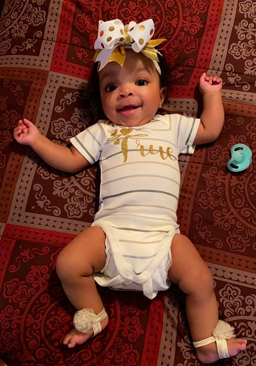 True is registered to the contest to win money with this photo: baby, baby_products, baby_toddler_clothing, cheek, costume_hat, eye, face, fun, happy, head, headband, headgear, headpiece, iris, magenta, pattern, person, pink, sleeve, smile