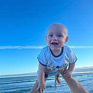 Mattéo participe au concours pour gagner de l'argent avec cette photo : baby, barefoot, blue_sky, child, fun, hands, happy, ocean, outdoor, person, playful, portrait, sea, sky, smiling, summer, sunlight, tshirt, vacation, water