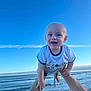 baby, barefoot, blue_sky, child, fun, hands, happy, ocean, outdoor, person, playful, portrait, sea, sky, smiling, summer, sunlight, tshirt, vacation, water
