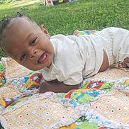 Clark Harris Jr is registered to the contest to win money with this photo: baby, blanket, child, clothing, cute, grass, happy, infant, lying_down, nature, outdoor, playing, plush_toy, shorts, smiling, socks, sunlight, toddler, toy, white_shirt