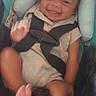 Clark Harris Jr is registered to the contest to win money with this photo: baby, smiling, car_seat, child, infant, seatbelt, happy, cute, clothing, person, face, hands, feet, sitting, indoors, child_seat, patterned_clothing, head_support, black_hair, infant_clothing