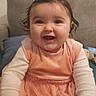 baby, bright, child, couch, cozy, cushion, cute, dress, hair_clip, happy, home, indoor, infant, long_sleeve_shirt, peach, person, portrait, sitting, smiling, wet_hair