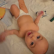 Rossi joined the competition — help win amazing prizes! baby, infant, diaper, blanket, plush_toy, lying_down, bedroom, smiling, big_eyes, playful, cute, bare_torso, toy, pillow, sheet, child, happy, looking_up, kicking_leg, floor_mat