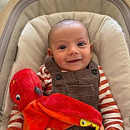 Lyam a rejoint le concours — aidez-le/la à gagner de superbes lots ! baby, infant, smile, plush_toy, octopus, striped_clothing, overalls, seat, cushion, indoor, child, happy, cute, hand, face, portrait, young, soft_toy, fabric, button