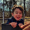 child, smiling, laughing, playground, swing, outdoor, park, woodland, trees, winter, jacket, happy, portrait, close_up, face, hands, playground_equipment, childhood, daylight, joy