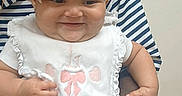 Aleyah joined the competition — help win amazing prizes! baby, child, infant, headband, bow, bib, smile, happy, person, adult_hand, striped_shirt, skin, indoor, holding, cute, small, portrait, face, clothing, human