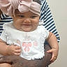 baby, child, infant, headband, bow, bib, smile, happy, person, adult_hand, striped_shirt, skin, indoor, holding, cute, small, portrait, face, clothing, human