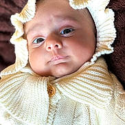 Nawaab joined the competition — help win amazing prizes! baby, infant, knitted_clothing, cream_color, hood, frill, button, blanket, soft_texture, close_up, portrait, face, eyes, pout, cozy, warm, child, cute, indoors, newborn