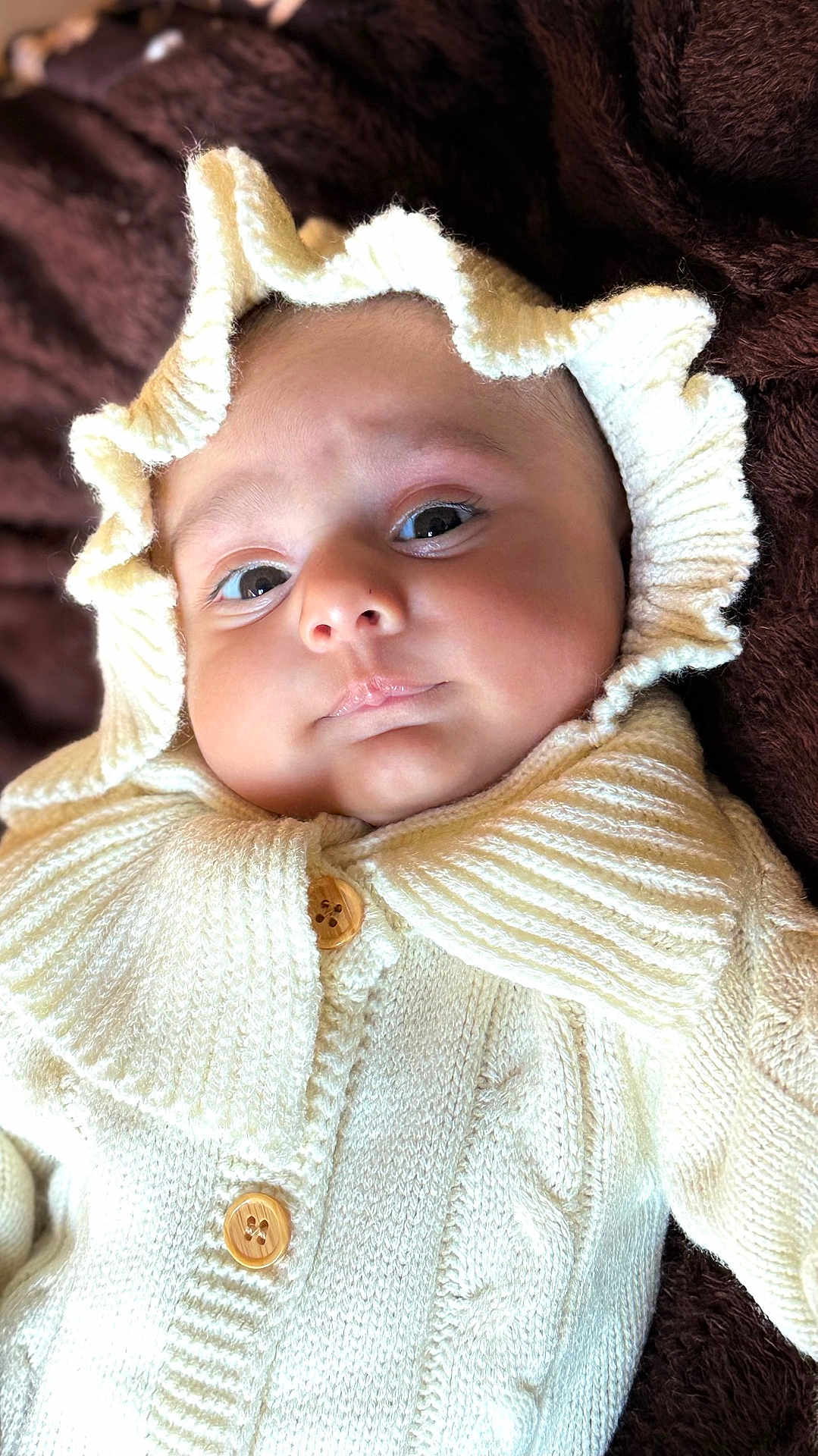 Nawaab joined the competition — help win amazing prizes! baby, infant, knitted_clothing, cream_color, hood, frill, button, blanket, soft_texture, close_up, portrait, face, eyes, pout, cozy, warm, child, cute, indoors, newborn