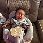 Alexander joined the competition — help win amazing prizes! baby, infant, child, smiling, happy, portrait, seated, elephant_plush, stuffed_toy, three_months, wooden_sign, bib, onesie, cuddling, leather_chair, indoor, close_up, facial_expression, baby_seat, family_photo