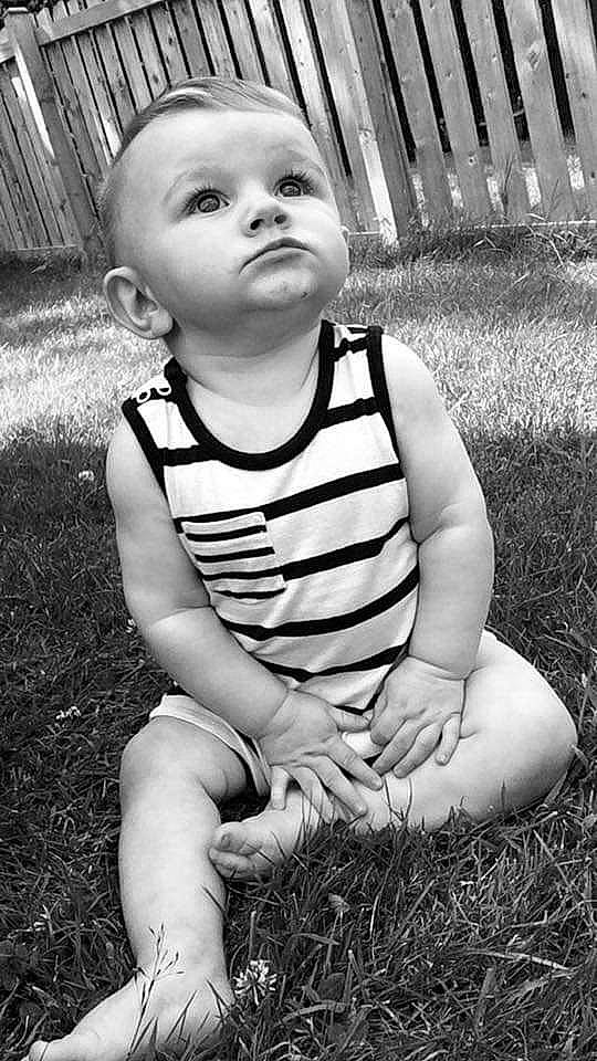 Archie-james is registered to the contest to win money with this photo: baby, black, black_and_white, child, eye, face, facial_expression, grass, head, headwear, monochrome, monochrome_photography, people, person, photograph, photography, sitting, skin, smile, standing