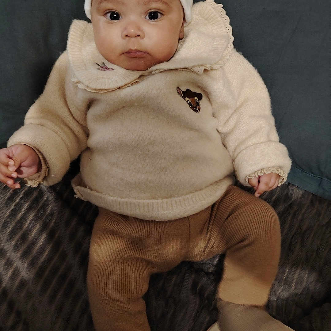 Méyya participe au concours pour gagner de l'argent avec cette photo : baby, blanket, child, comfortable, couch, cozy, cute, face, hat, headwear, indoor, infant, knitwear, looking, pants, person, portrait, seated, socks, sweater