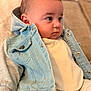 baby, child, denim_jacket, clothing, couch, face, head, infant, indoors, neutral_background, person, portrait, seated, soft_texture, warm_colors, young_child, cute, casual_wear, button, hood